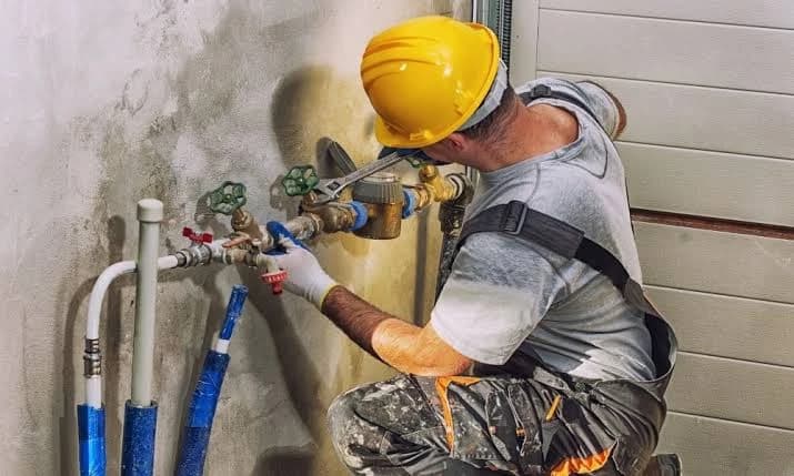 Plumber installing a shutoff valve on an exterior line at an Alpharetta, GA home
