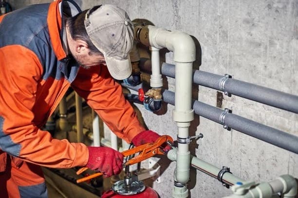 Plumber repairing overhead supply pipes in an Alpharetta, GA utility room